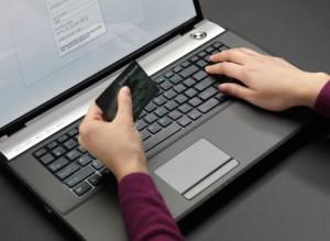 Woman sitting at a laptop and entering her credit card information into an online form