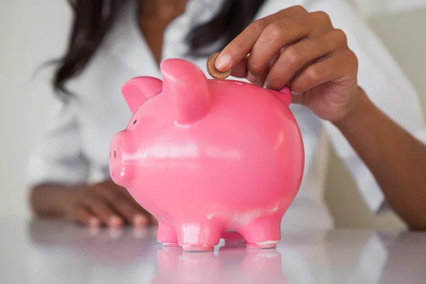 Предприниматель, положить монеты в копилку — стоковое изображение Предприниматель, положить монеты в копилку — стоковое фото
