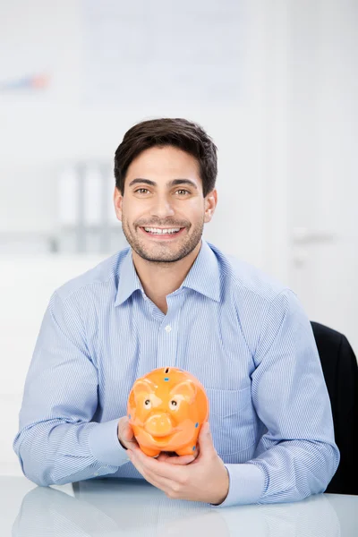Бизнесмен, холдинг копилку на стол — стоковое изображение Бизнесмен, холдинг копилку на стол — стоковое фото